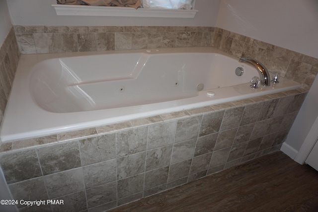 bathroom with wood-type flooring and tiled bath