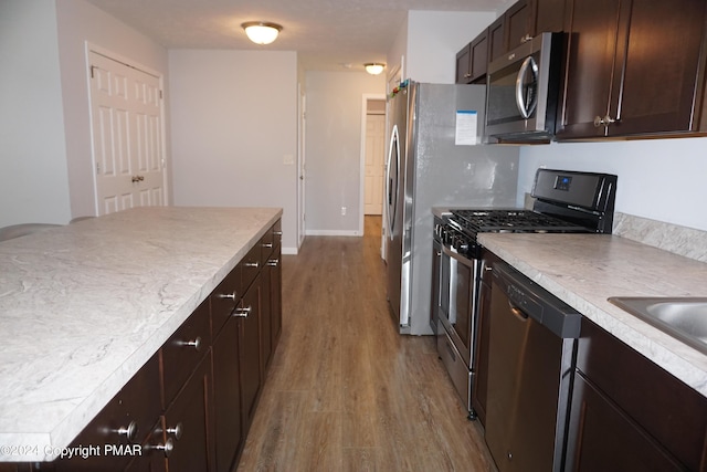 kitchen featuring dark brown cabinetry, light hardwood / wood-style flooring, and stainless steel appliances