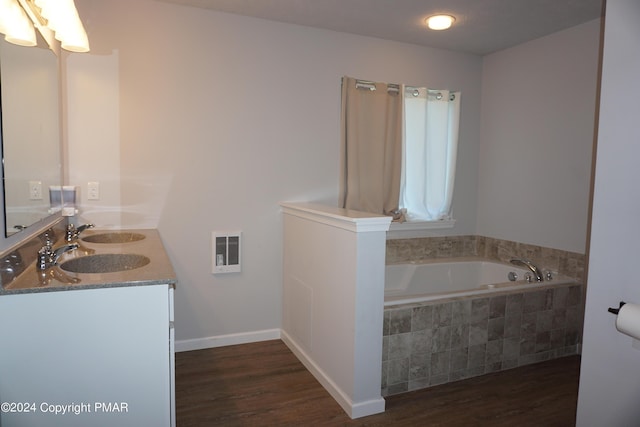 bathroom featuring vanity, hardwood / wood-style flooring, and a relaxing tiled tub