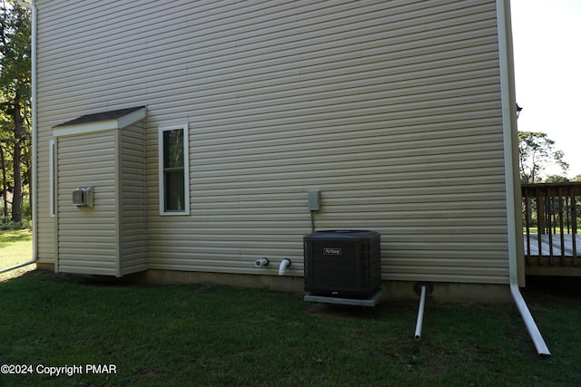 view of property exterior with a wooden deck, cooling unit, and a lawn