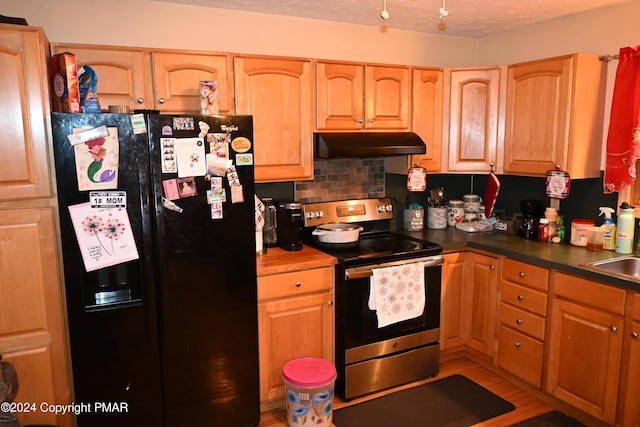 kitchen with a textured ceiling, under cabinet range hood, a sink, black fridge with ice dispenser, and electric stove