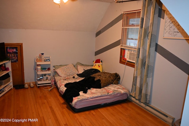 bedroom featuring a baseboard heating unit, wood finished floors, and lofted ceiling