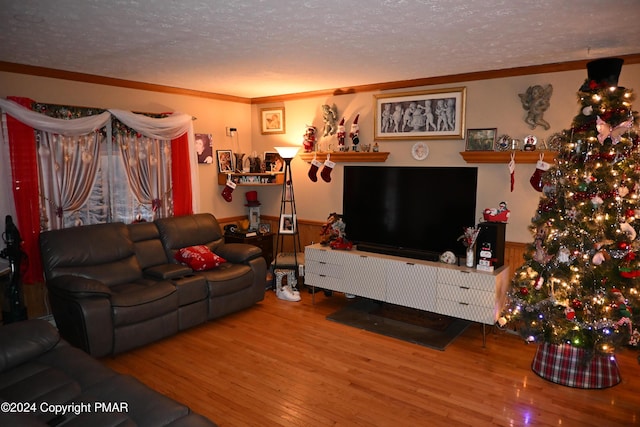 living room featuring a textured ceiling, wainscoting, wood finished floors, and crown molding