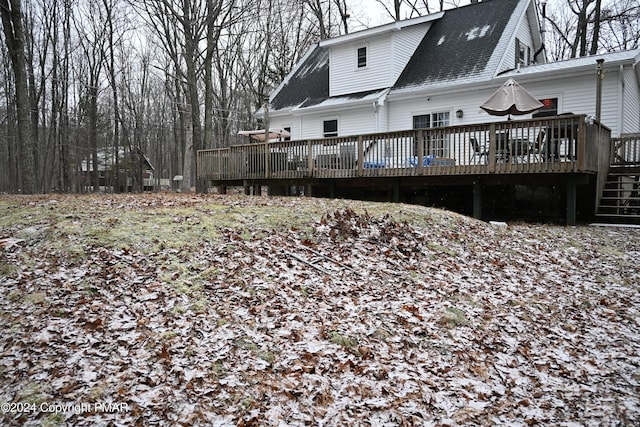 back of property with a deck and roof with shingles