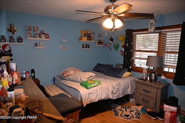 bedroom with a ceiling fan, a textured ceiling, and wood finished floors