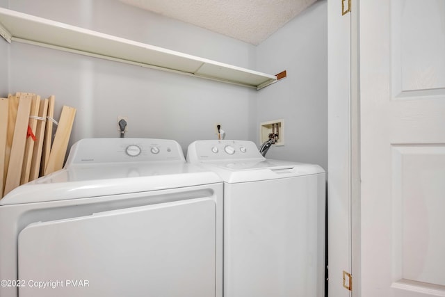 clothes washing area with laundry area, separate washer and dryer, and a textured ceiling