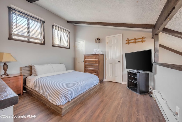 bedroom with vaulted ceiling with beams, a baseboard heating unit, a textured ceiling, and wood finished floors