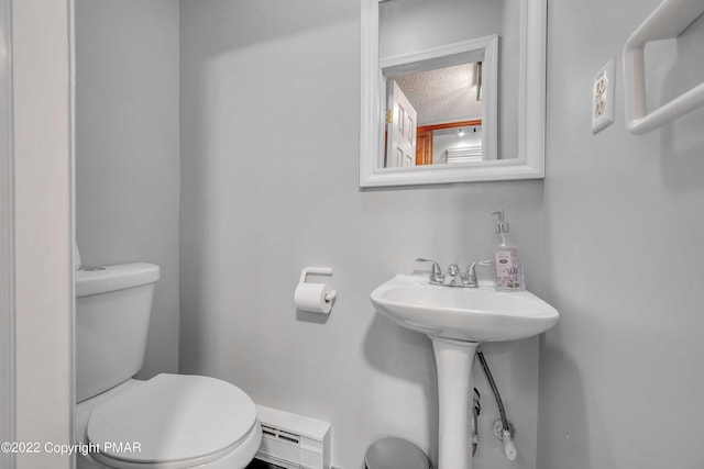 bathroom with a baseboard radiator, sink, a textured ceiling, and toilet