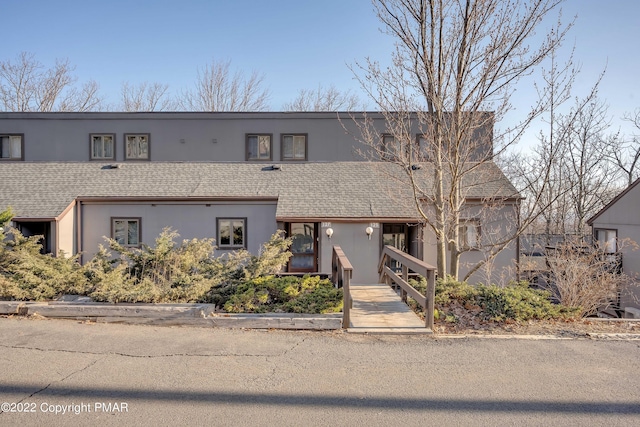 view of property with a shingled roof and stucco siding