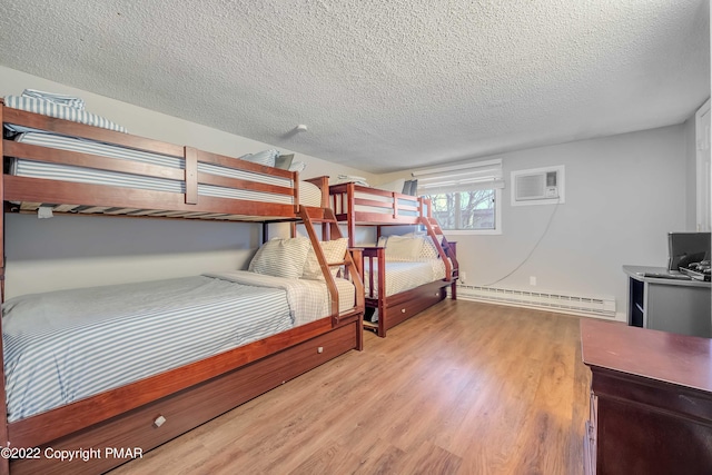 bedroom featuring light wood-style floors, an AC wall unit, a textured ceiling, and baseboard heating