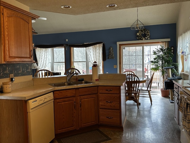 kitchen with light countertops, a sink, dishwasher, a textured ceiling, and brown cabinets