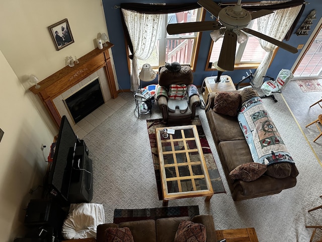 living area with ceiling fan and a tile fireplace