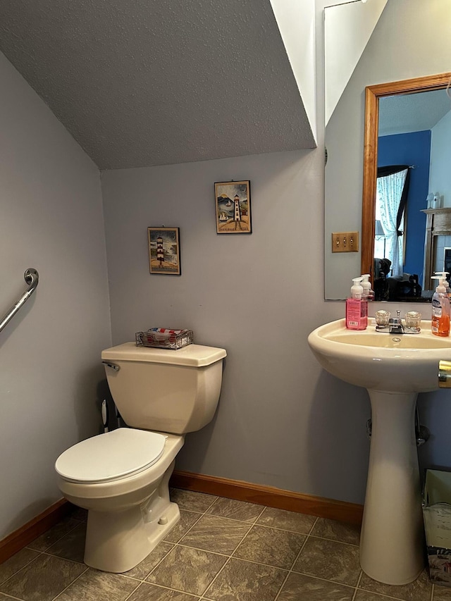 half bath featuring toilet, baseboards, and a textured ceiling