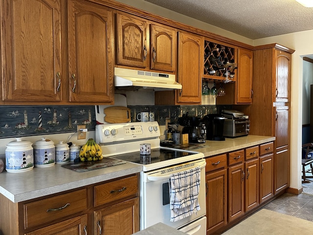 kitchen with white electric range, light countertops, under cabinet range hood, and brown cabinetry