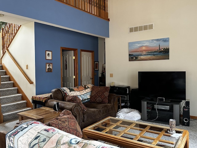 living area featuring visible vents, a high ceiling, carpet, and stairway