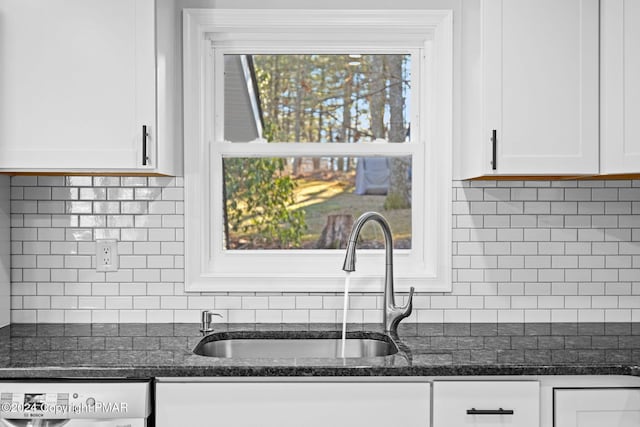 kitchen with dishwasher, dark stone countertops, a sink, and white cabinets