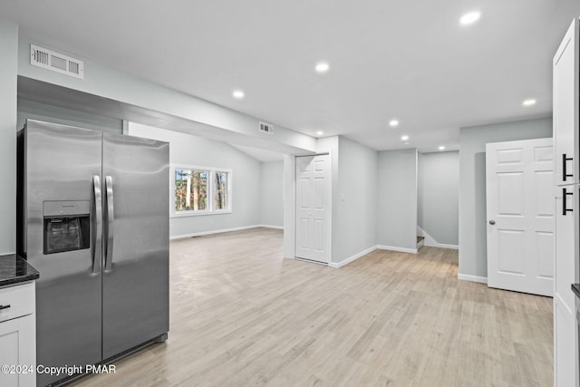 kitchen with light wood finished floors, stainless steel fridge, visible vents, and open floor plan