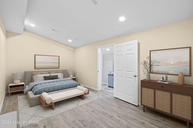 bedroom featuring baseboards, light wood-type flooring, ensuite bath, and recessed lighting