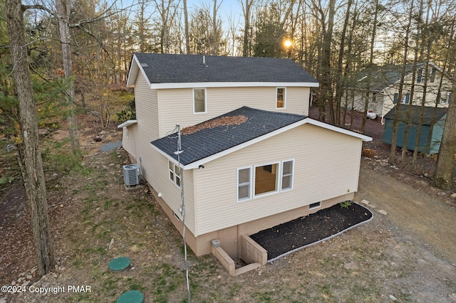 back of house with central AC and a shingled roof