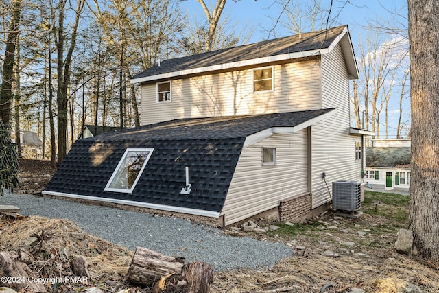 view of side of home featuring a shingled roof and central AC