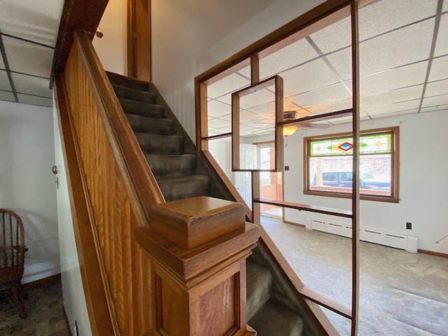 stairs with baseboards, a baseboard radiator, carpet, and a drop ceiling