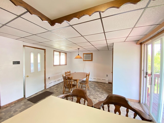 dining space featuring a baseboard heating unit, a wall unit AC, and a drop ceiling