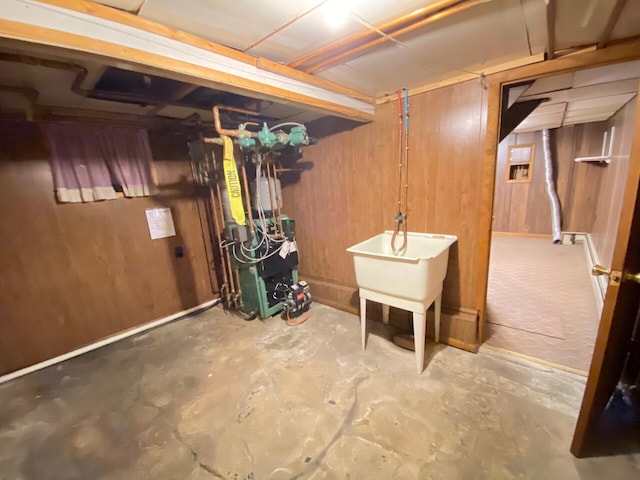 unfinished basement with a heating unit, wood walls, and a sink