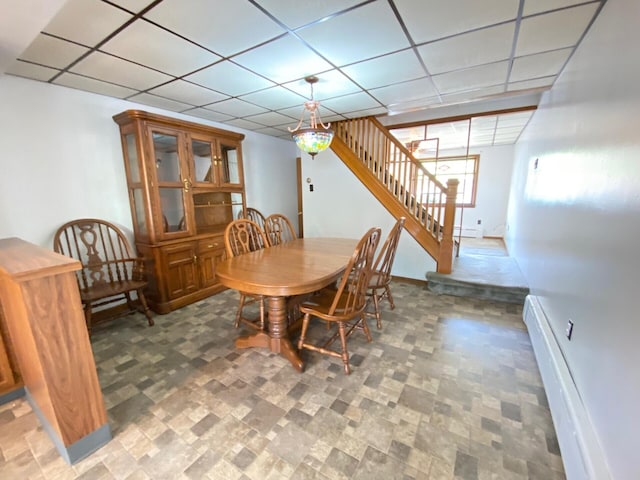 dining area with stairway, baseboards, a drop ceiling, and a baseboard heating unit