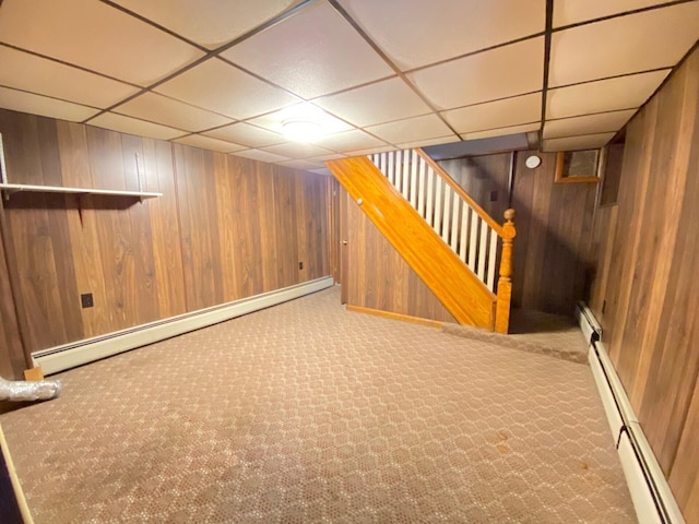 finished below grade area featuring a baseboard radiator, carpet, and a drop ceiling