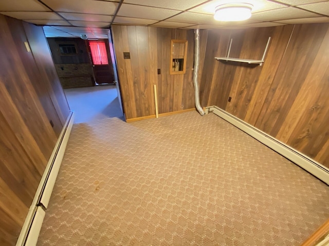 finished basement with baseboards, a baseboard radiator, and wood walls