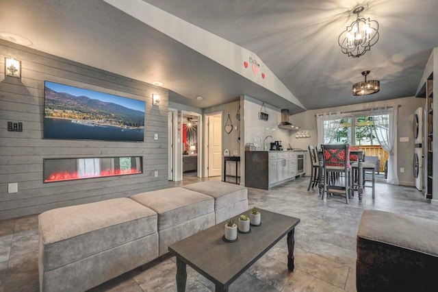 living area with lofted ceiling, a glass covered fireplace, a chandelier, beverage cooler, and washer / dryer