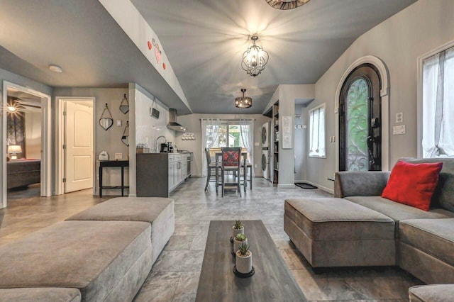 living room with a chandelier, vaulted ceiling, baseboards, and washer / clothes dryer