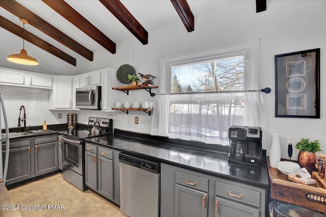 kitchen featuring dark countertops, appliances with stainless steel finishes, a sink, gray cabinets, and backsplash