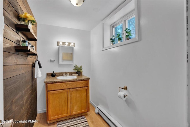 bathroom featuring a baseboard heating unit, wood finished floors, and vanity