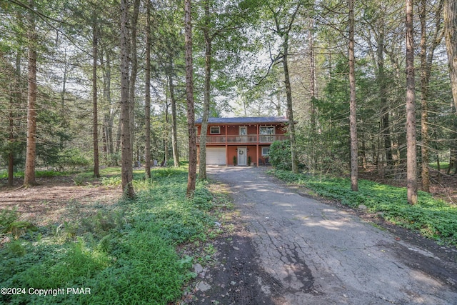 rustic home featuring a garage, driveway, and a wooded view