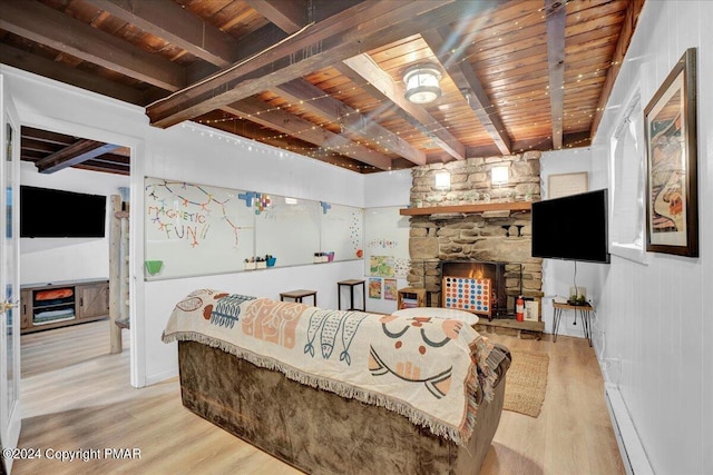 living room with wooden ceiling, wood finished floors, baseboard heating, a stone fireplace, and beam ceiling