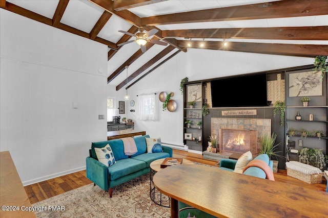 living area featuring vaulted ceiling with beams, a ceiling fan, wood finished floors, and a tile fireplace