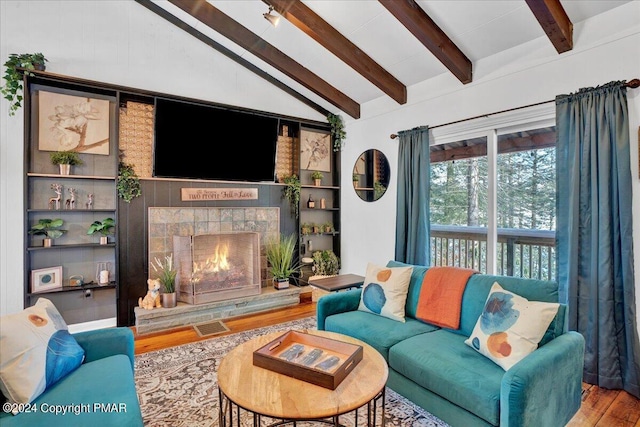 living area featuring lofted ceiling with beams, a fireplace, visible vents, and wood finished floors