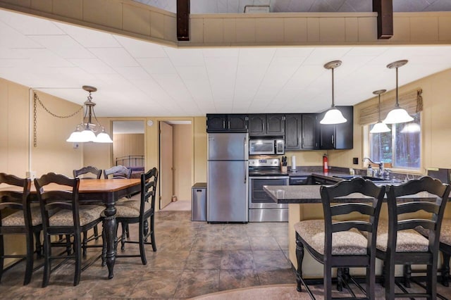 173 Pontiac Path, Pocono Lake, PA 18347 - kitchen with appliances with stainless steel finishes, dark countertops, hanging light fixtures, a peninsula, and a breakfast bar