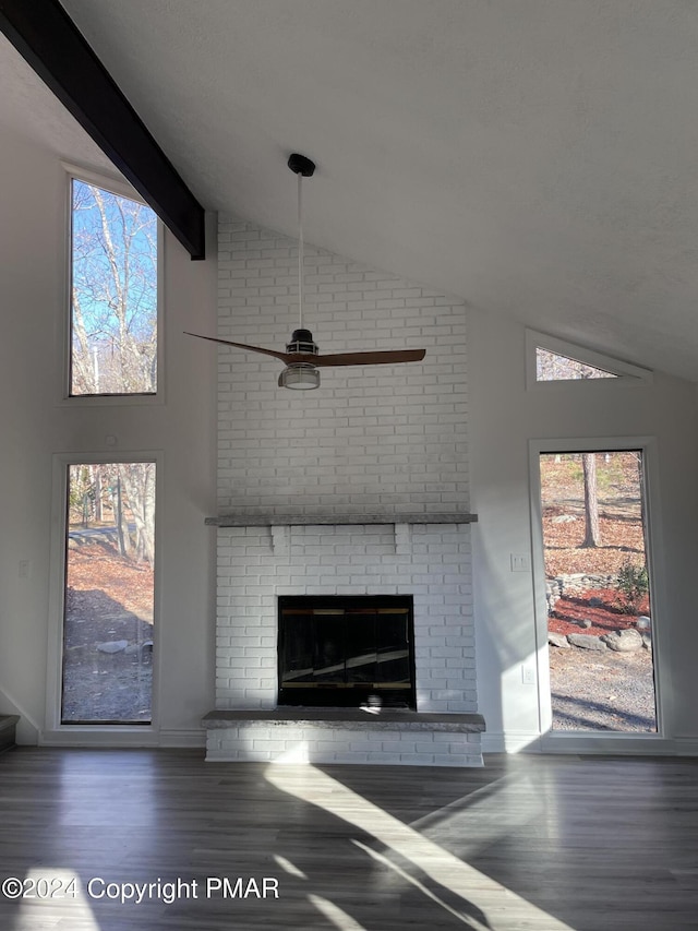 unfurnished living room with lofted ceiling with beams, a ceiling fan, wood finished floors, and a fireplace