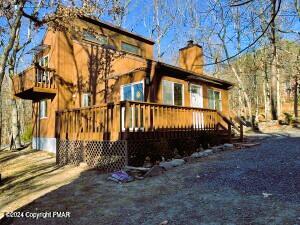 back of house featuring a wooden deck and a chimney