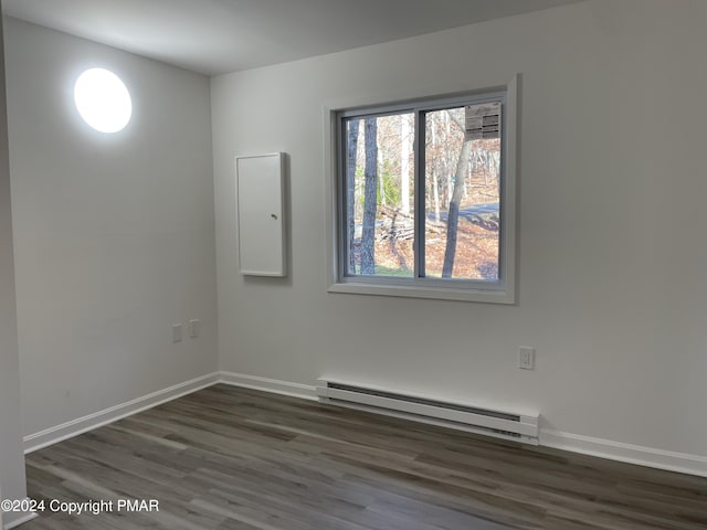 empty room with wood finished floors, baseboards, and a baseboard radiator