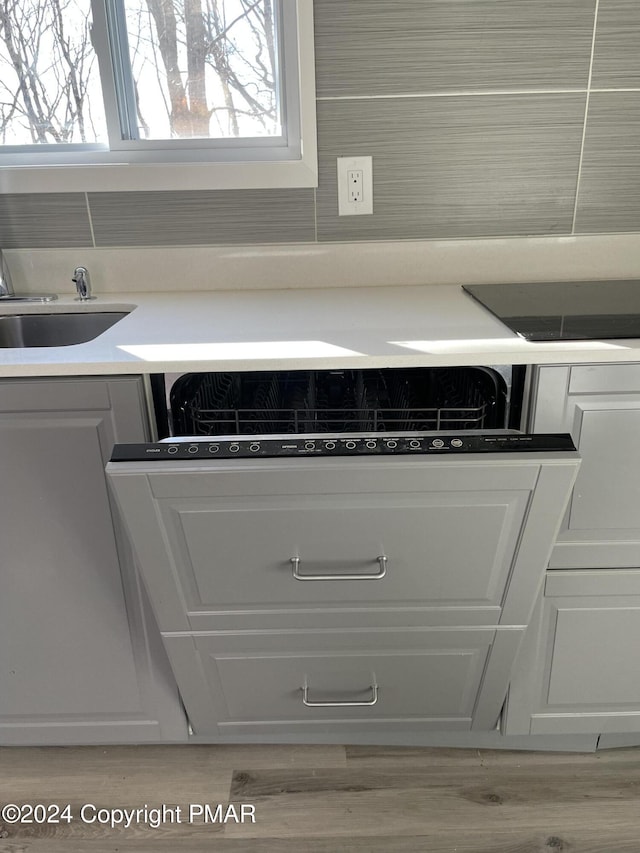 interior details featuring a sink, light wood-style floors, and backsplash