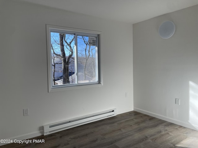 empty room with baseboard heating, dark wood-type flooring, and baseboards