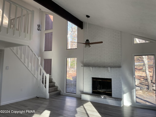 unfurnished living room featuring a wealth of natural light, beamed ceiling, and stairs