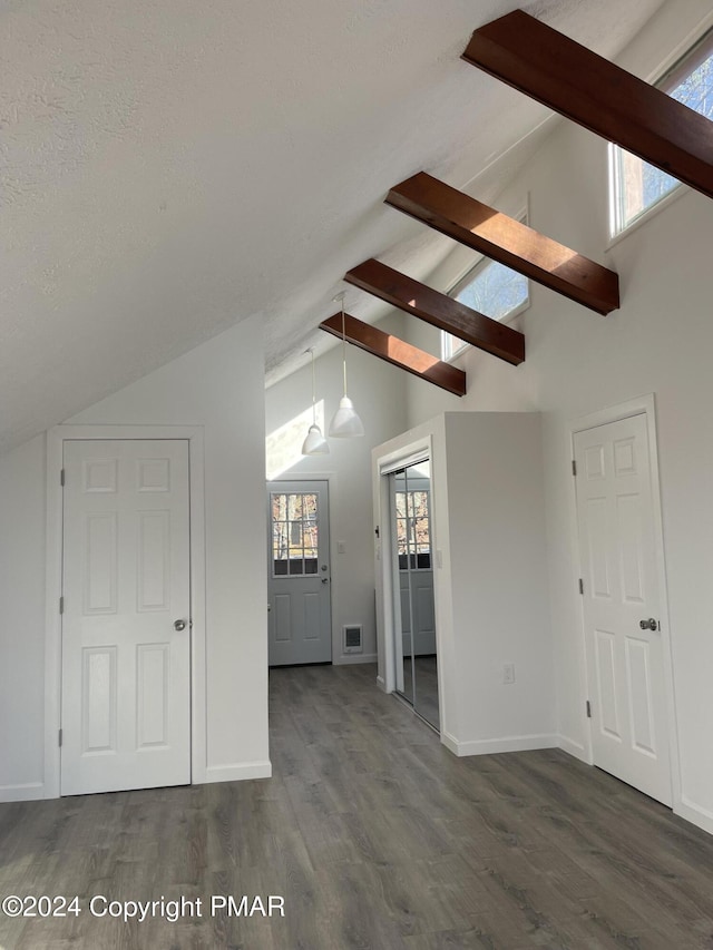 interior space with visible vents, lofted ceiling with beams, a textured ceiling, baseboards, and dark wood-style flooring