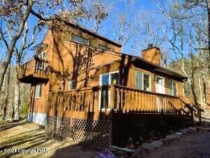 back of house with a wooden deck and a chimney