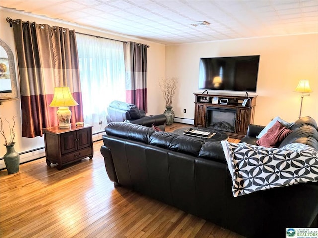 living room with hardwood / wood-style flooring, a baseboard radiator, a fireplace, and a baseboard heating unit