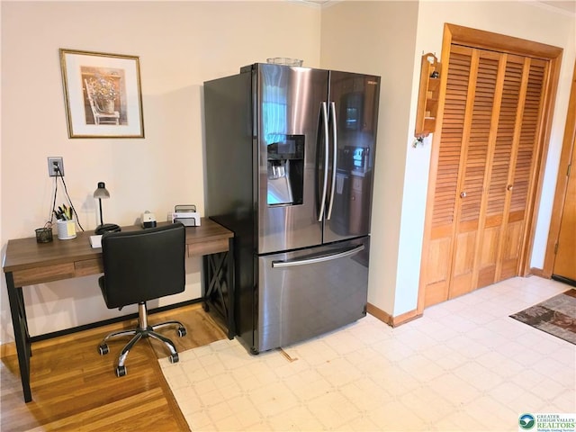 kitchen with stainless steel refrigerator with ice dispenser, baseboards, a desk, and light wood-style flooring