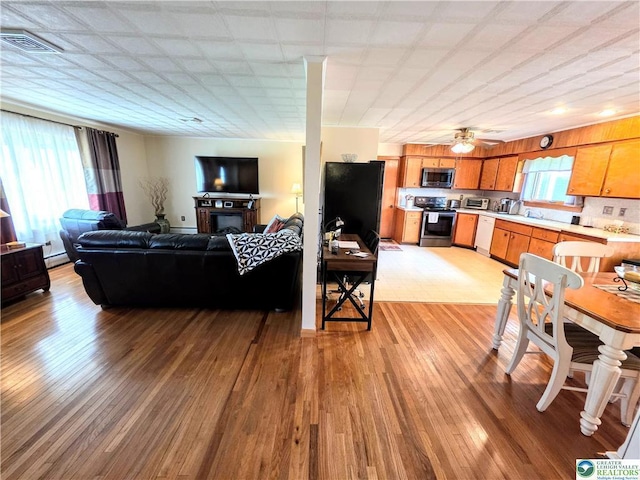 living area featuring light wood-type flooring and a baseboard heating unit